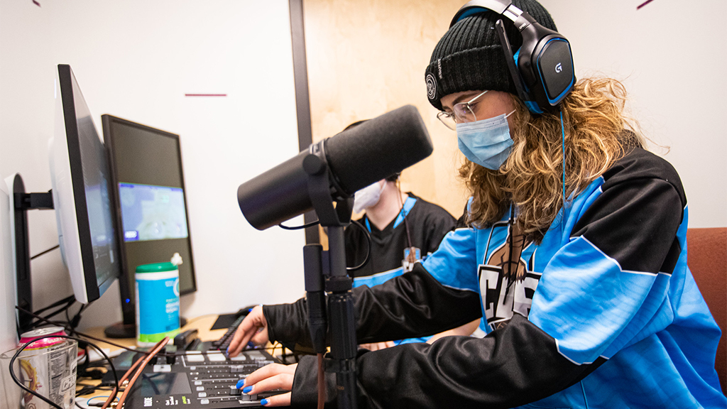 Student working on a mixing board with a microphone and a computer